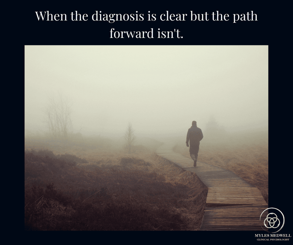 Person walking alone on a foggy boardwalk path with quote "When the diagnosis is clear but the path forward isn't" - Myles Medwell Psychology Richmond Melbourne